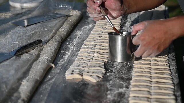 Hand shaping fresh dough flour dusted rustic kitchen outdoor cooking homemade noodle artisan handcraft preparation texture rich mood with calm focus and care handmade dough strip flour dusted table