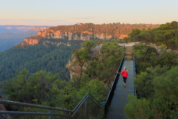 Woman on metal bridge crossing mountain ravine in Blue Mountains
