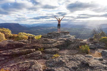 Woman on mountain peak.  Praise or triumph arms outstretched to the heavens