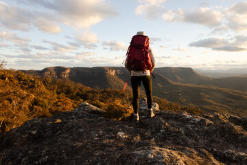 Hiker stands on rocky cliff views overlooking valley