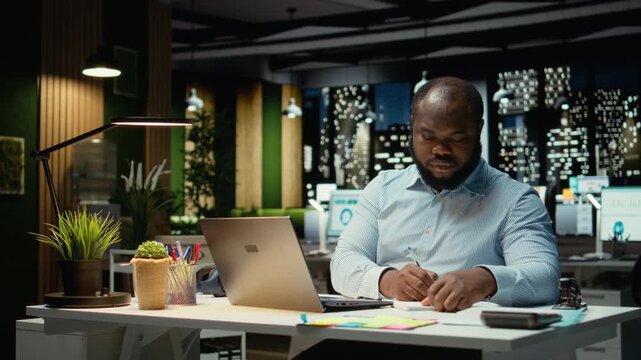 African american strategist ripping a paper after writing the wrong idea, restarting work in rage and crumpling the page sheet. Discontent man does a typo mistake while transcribing. Camera A.