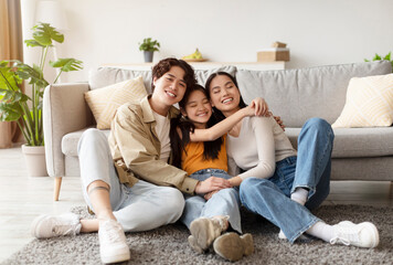 Obraz premium Three friends sit closely together on a sofa in a well-lit living room, sharing smiles and laughter. They display warmth and happiness while enjoying each other's company.