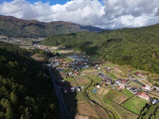 A rural area with houses and a river. The houses are spread out and there are a few trees in the background