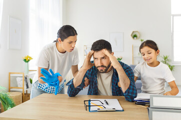 Sad father under stress trying to work, mischievous child and arguing wife distract man at home....