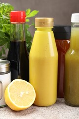 Bottles of different tasty sauces and products on grey table, closeup