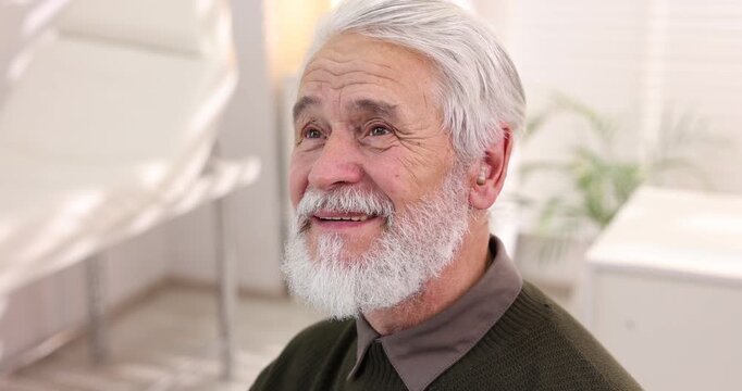 Doctor putting hearing aid into senior man's ear in hospital, closeup