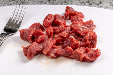 A heap of cut up beef steak for stir fry on a white cutting board