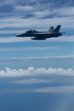 View of an Australian RAAF FA18 Super Hornet flying at altitude above a cloud bank.