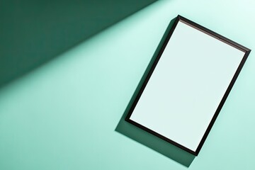 A blank frame casts a shadow on a teal background under bright light.