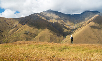 Lone hiker standing in grassland enjoying peaceful mountain scenery in Juta Village, Georgia. A...