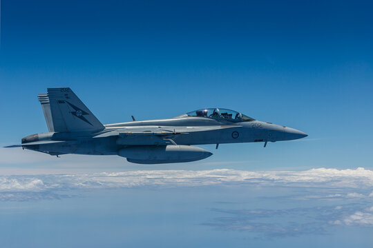 An Australian RAAF FA18 Super Hornet flying at altitude against a blus sky.