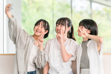 Elementary and junior high school girls in casual clothes with friends (smartphone, selfie)
