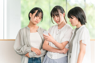 A girl in elementary school or junior high school dressed in casual clothes looking sulky while looking at her smartphone (dissatisfaction, stress, sigh)
