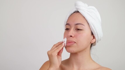 Young woman using cotton pad for skin care routine - Powered by Adobe