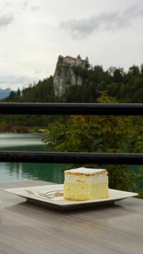 Bled cream cake Kremsnita on plate at Kavarna Park Cafe in Bled, Slovenia by lake water, vertical pan