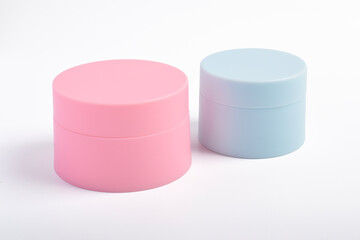Pink and blue cosmetic jars isolated on a white background.