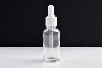 Clear glass dropper bottle on dark background. Packaging mockup