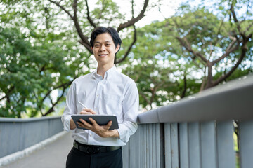 Fototapeta premium Portrait of businessman using digital tablet while standing in park. 