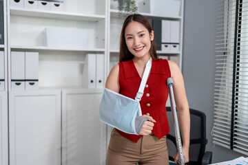 Portrait of injured Asian businesswoman wearing hand splint in office. 