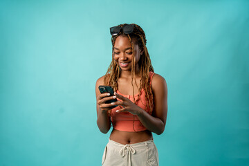 African American woman holding smartphone in isolated blue background.