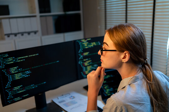 Caucasian young female software engineer working at night in the office. 