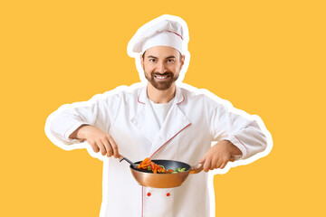 Handsome bearded chef frying vegetables on yellow background