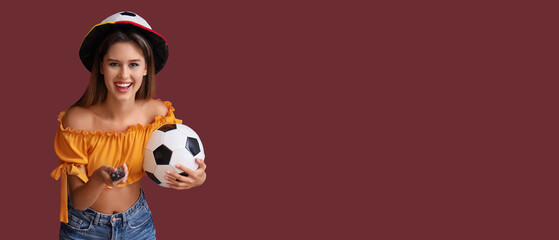 Young woman with TV remote controller watching football on red background with space for text