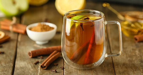 Glass cup of tasty fruit tea with cinnamon on table