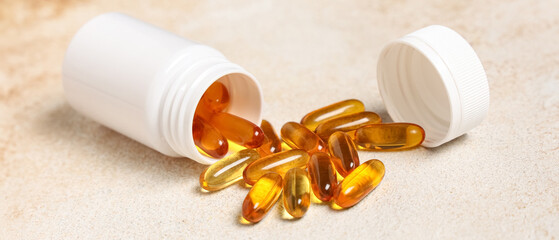 Jar of vitamin E capsules on light background, closeup