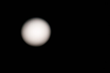 Circular blurry spooky moon on left of image in sky on background with copy-space,