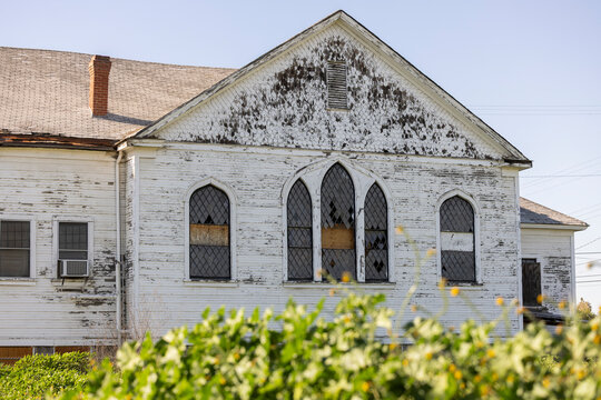 Shrubs frame a historic church in downtown Fowler, California, USA.