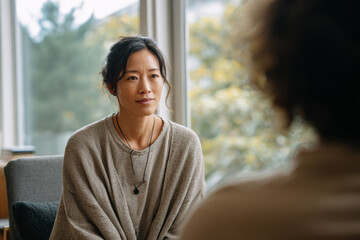 A young Asian woman attends an individual psychotherapy session, looking focused as she confides in the therapist.
