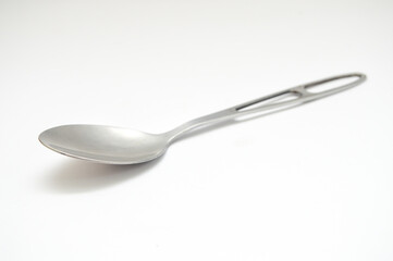 Close-up of a modern, shiny stainless steel spoon with a hollowed handle, isolated diagonally on a pure white background. Represents cutlery, food concept, minimalist kitchenware, and object.