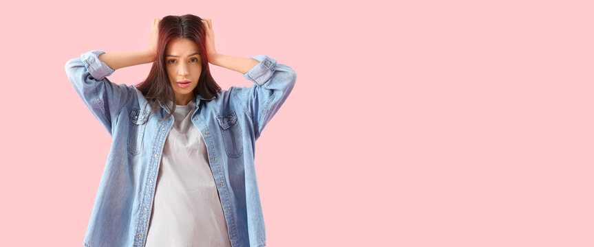 Portrait of worried young woman on pink background