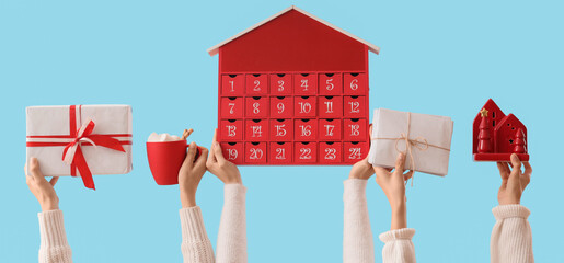 Female hands with Christmas gift, advent calendar, letters and cup of cocoa drink on color...