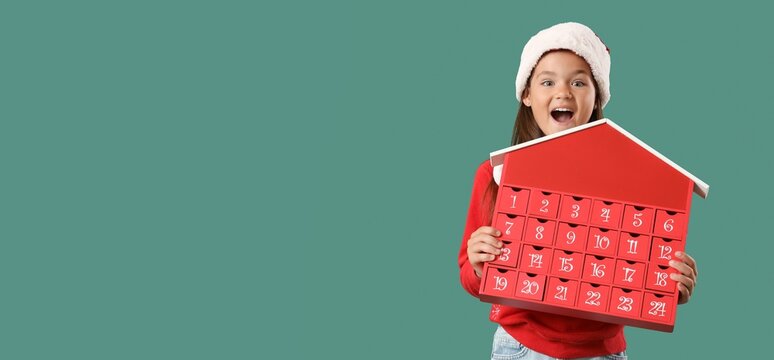 Excited girl in Santa hat and with Christmas Advent calendar on green background with space for text