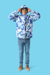 Young man in winter clothes on color background