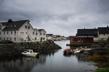 Obraz premium Moored boats rest beside colorful houses in Henningsvær, Lofoten.