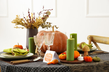 Festive table setting for Thanksgiving Day with pumpkins, greeting card and burning candles