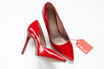 Stylish high heeled shoes and sale tag on white background. Black Friday