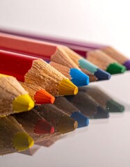 Close-up of colorful sharpened pencils lined up on a reflective surface
