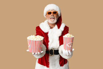 Santa Claus in 3D glasses with buckets of tasty popcorn on brown background