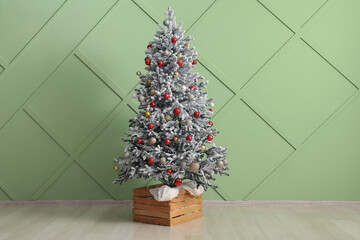 Fir tree decorated with beautiful Christmas balls near color wall