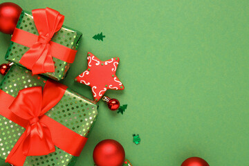 Beautiful composition with Christmas gifts, balls and gingerbread on green background