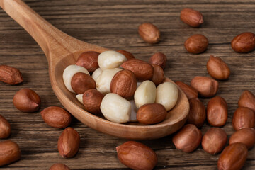 Close-Up of Raw Brown and Skinned Peanuts in a Wooden Spoon on a Rustic Wood Background