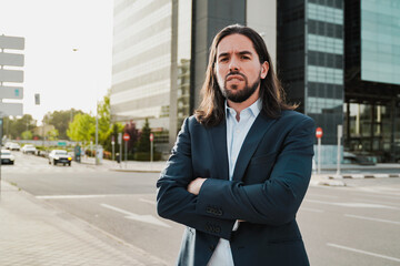 Hispanic business man looking at camera with office buildings on background – Confident entrepreneur in the city
