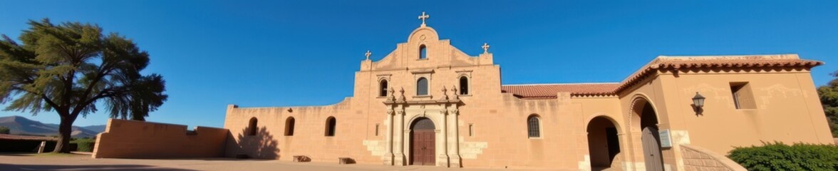Fototapeta premium Historic adobe ruins of a Spanish mission church against a clear blue sky, weathered, landscape