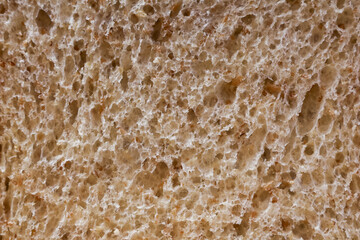 Comforting macro close up of brown bread slice food texture. This whole wheat porous background reveals intricate detail of crumb for rustic, wholesome feel