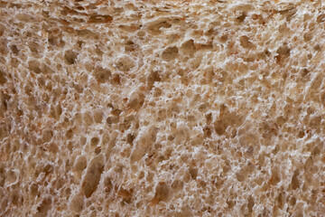 Macro close up background of brown whole wheat bread texture. porous crumb and fresh surface detail wholesome, organic, healthy food, staple ingredient for breakfast