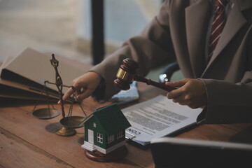 Real Estate Law, Home Insurance, property Tax, Auction and Bidding concepts. small toy house model with gavel justice hammer on desk in courthouse.